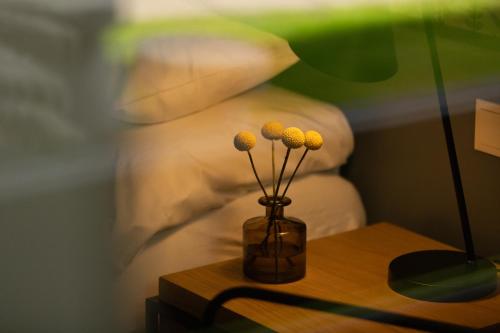 a vase with flowers on a table next to a bed at Das Esel - Kleinod in Rust in Rust