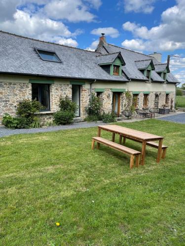 a wooden bench sitting in front of a building at Gîte à la campagne in Airel