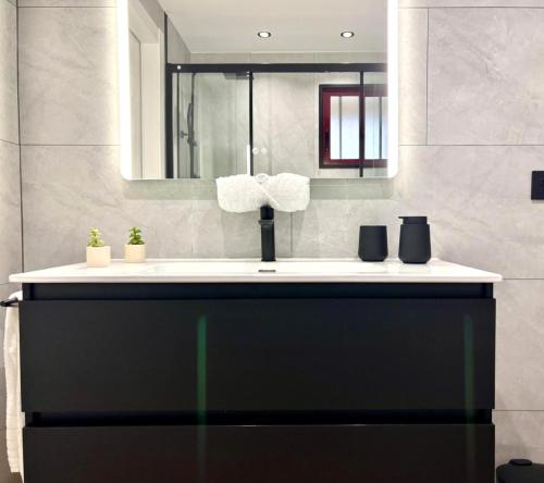 a bathroom with a sink and a mirror at Holibai, Meiga Do Mar, Apto moderno, vistas al mar y playa cerca, Baiona in Baiona