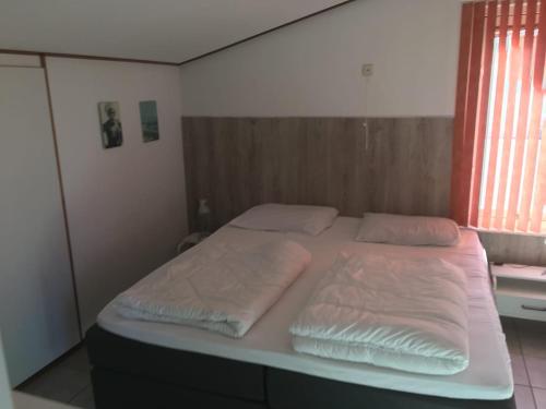 a bed with two pillows on it in a bedroom at freistehendes Ferienhaus mit Sauna und Kamin in Kamperland