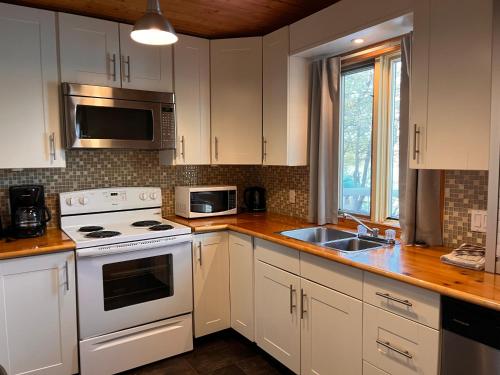 a kitchen with white cabinets and a stove and a sink at Camping Chalets Lac St-Augustin in Quebec City