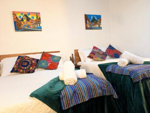 a bedroom with two beds with blankets and pillows at Casa Quetzalli, Los Nazarenos in Antigua Guatemala