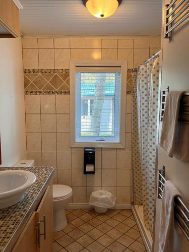 a bathroom with a sink and a toilet and a window at Camping Chalets Lac St-Augustin in Quebec City
