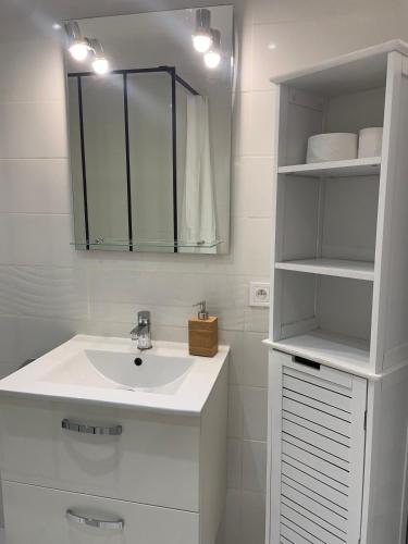 une salle de bain blanche avec un lavabo et un miroir dans l'établissement Escapade en Champagne, à Troyes