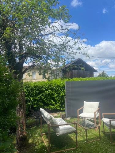 two chairs and a table and two chairs in a yard at L entre cœur des deux mers in Cadillac