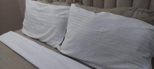 two white pillows sitting on top of a bed at Serene BnB - Apt 01 Makongo after Mlimani City in Dar es Salaam