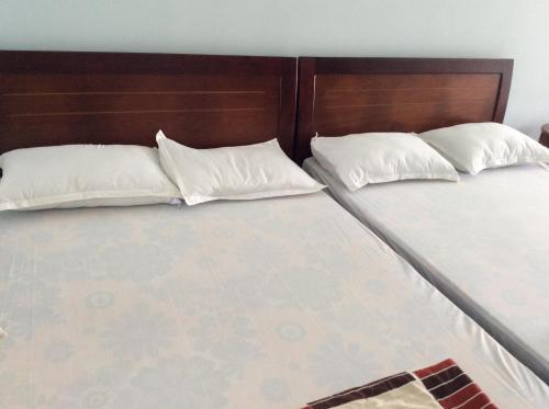 two beds with white pillows sitting next to each other at Quốc Ân Motel in Long Hai