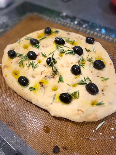 a pizza with cheese and olives on a table at Le vieux clos du rucher kêr-melen in Paimpol