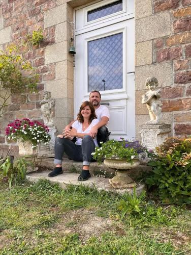 a man and a woman sitting in front of a door at Le vieux clos du rucher kêr-melen in Paimpol