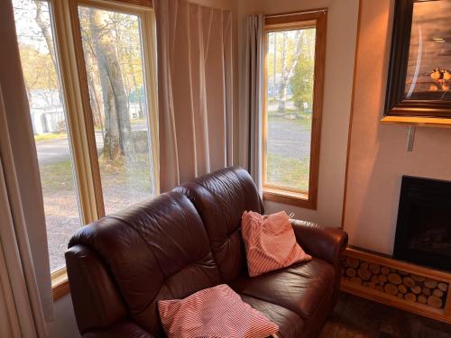 a brown leather couch in a living room with windows at Camping Chalets Lac St-Augustin in Quebec City
