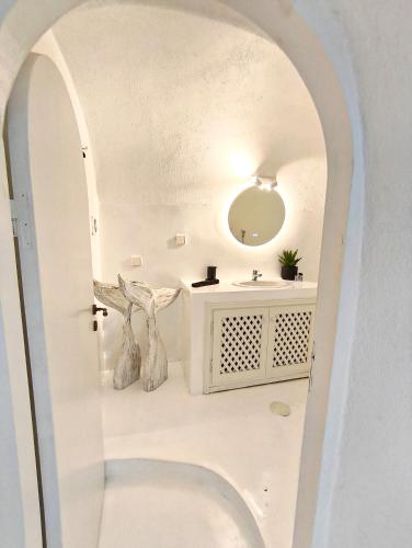 a white bathroom with a sink and a mirror at The Magic Luxury Cave Suites in Vóthon