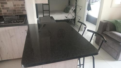 a black counter top in a kitchen with a living room at Chakas Rock Chalet 57 in Ballito