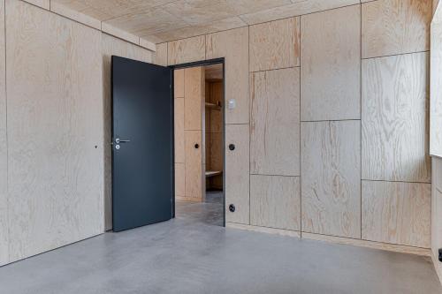 an empty room with a door and wooden walls at Kivikshusen in Kivik