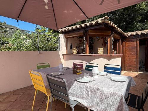 - une table et des chaises sur une terrasse avec un parasol dans l'établissement Maison vue mer 4 chambres - 7 min plage, à Cavalaire-sur-Mer