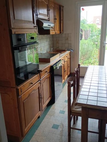 une cuisine avec des armoires en bois, une table et une fenêtre dans l'établissement Logement entier, à Nemours