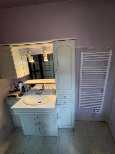 une salle de bain blanche avec un lavabo et un miroir dans l'établissement Logement entier, à Nemours