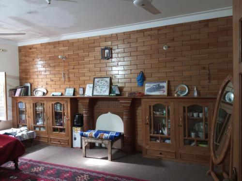 a living room with a brick wall and wooden furniture at WindyCrest Inn in Chitral
