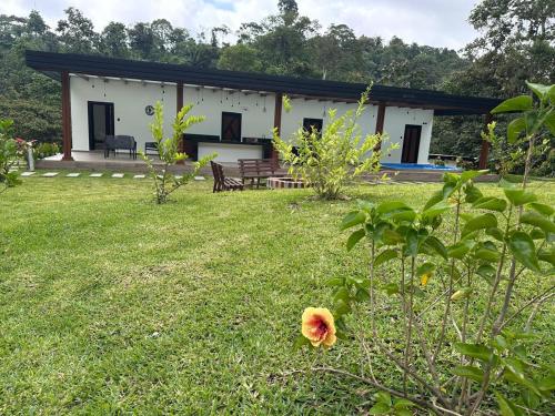 a small white house with a grassy yard at Casa de la Cascada in Pedro Vicente Maldonado