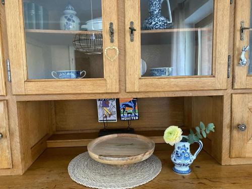 a wooden cabinet with a bowl and a vase at Ferienwohnung an der Berkelquelle in Billerbeck
