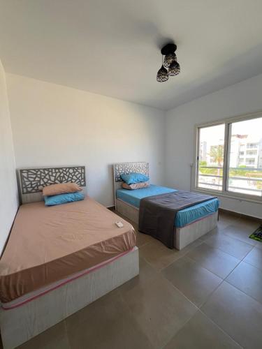 a bedroom with two beds and a large window at Amwaji in El Alamein