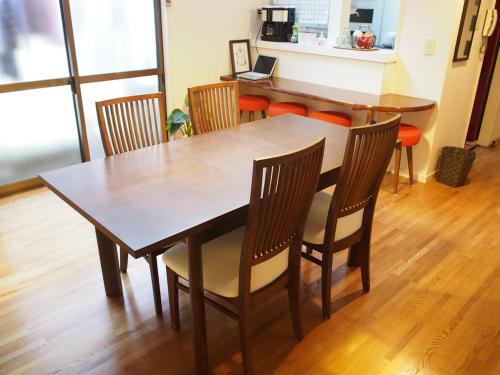 a dining room table with chairs and a table with a laptop at Guesthouse Ten-roku - Female Only in Osaka