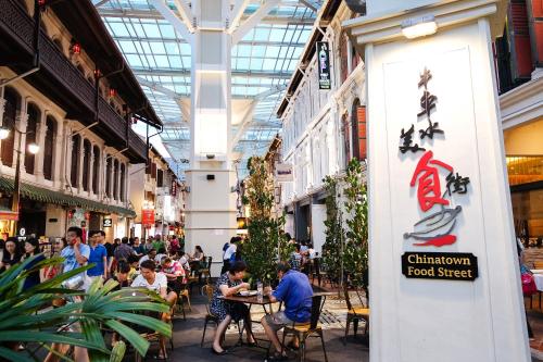 a group of people sitting at tables in a shopping mall at Hotel Clover 7 in Singapore