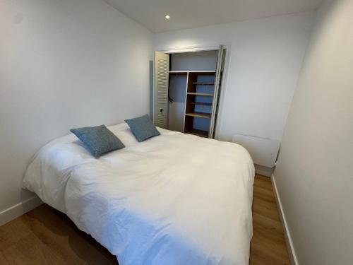 une chambre avec un lit blanc avec deux oreillers bleus dans l'établissement Appartement vue mer 45m2 avec grande terrasse 20m2, à La Baule
