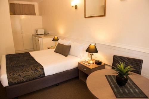 a hotel room with a bed and two tables at Garden City Motor Inn in Brisbane