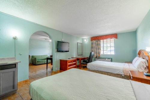 a bedroom with two beds and a desk and a television at Lone Star Inn & Suites by OYO Harlingen TX in Harlingen