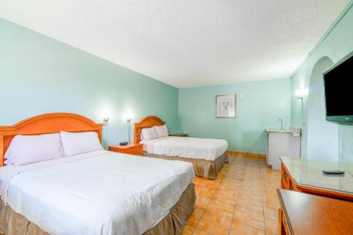a hotel room with two beds and a flat screen tv at Lone Star Inn & Suites by OYO Harlingen TX in Harlingen