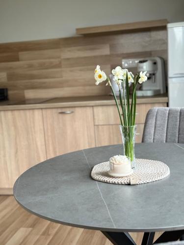 a vase of flowers on a table in a kitchen at Poilsis Kunigiškiuose in Palanga