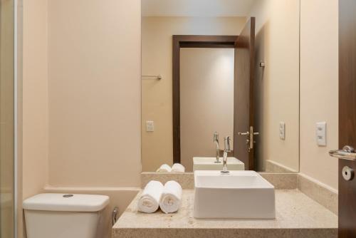a bathroom with a sink and a toilet and a mirror at Transamerica Dunas de Marapé in Jequia da Praia