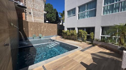 a house with a swimming pool next to a building at Aline Duque 308 no Centro de Porto by La Playa in Porto De Galinhas