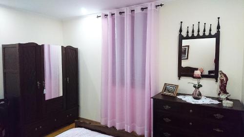 ラメーゴにあるDouro Valley - Casa Vale do Douroのピンクのカーテン、ドレッサー、鏡が備わるベッドルーム1室