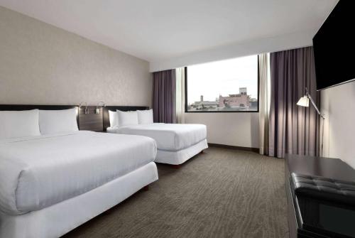 a hotel room with two beds and a window at Wyndham Monterrey Ambassador Centro in Monterrey