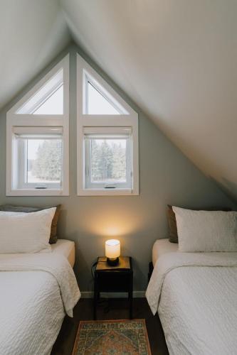 two beds in a room with two windows at Abraham - Peaceful Tiny Cabin In Historic Nordegg in Nordegg
