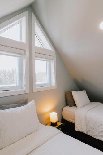a bedroom with two beds and two windows at Abraham - Peaceful Tiny Cabin In Historic Nordegg in Nordegg