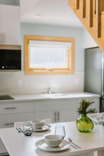 a white kitchen with a table with plates and glasses at Abraham - Peaceful Tiny Cabin In Historic Nordegg in Nordegg