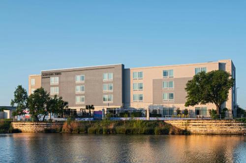 a large building next to a body of water at SpringHill Suites by Marriott Austin Cedar Park in Cedar Park