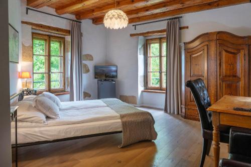 a bedroom with a bed and a desk and windows at Hôtel La Maison du Prussien in Neuchâtel