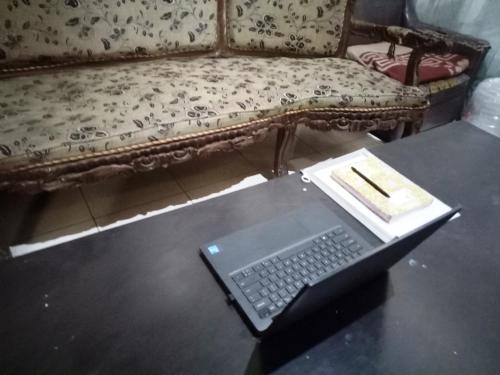 a laptop on a table in front of a couch at Hotel O Homestay Rungkut Syariah in Surabaya