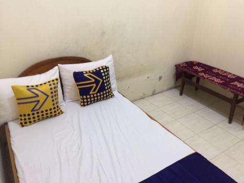 a bedroom with a bed with yellow and blue pillows at Hotel O Homestay Rungkut Syariah in Surabaya