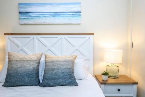a bed with a white headboard and a table with a lamp at Paradise on Pascoe in Apollo Bay