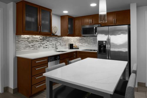 a kitchen with a table and a stainless steel refrigerator at Residence Inn by Marriott Daytona Beach Oceanfront in Daytona Beach
