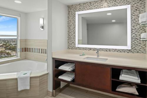 a bathroom with a tub and a sink and a mirror at Residence Inn by Marriott Daytona Beach Oceanfront in Daytona Beach