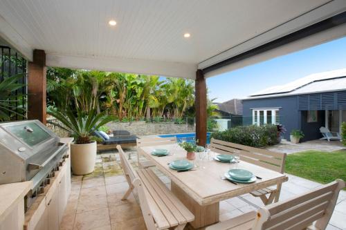 a patio with a table and chairs and a pool at Spacious Oceanview Escape with Pool and Cabana in Collaroy