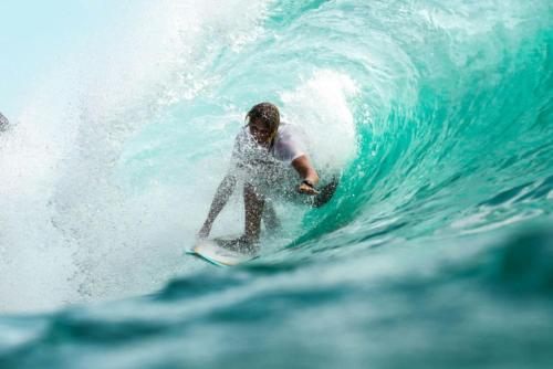 a man riding a wave on a surfboard in the ocean at Spacious Oceanview Escape with Pool and Cabana in Collaroy
