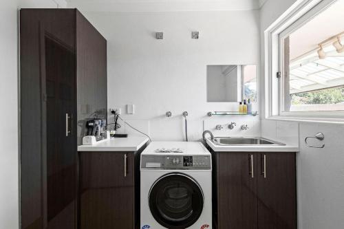 a kitchen with a washing machine and a sink at Bayswater Retreat, 3 Bed house. in Perth