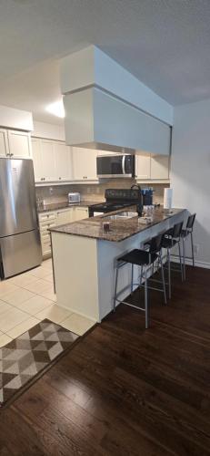 a kitchen with a counter with chairs and a refrigerator at Lovely condo near Lake Ontario in Toronto