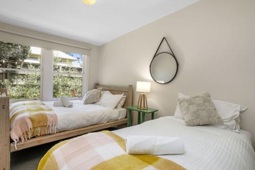 2 camas en un dormitorio con espejo en la pared en Red Door - Centrally Located, en Apollo Bay
